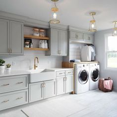 a washer and dryer sitting in a kitchen next to a window with lights on