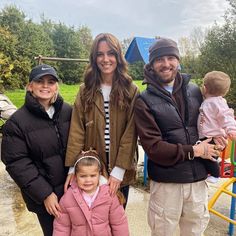 two adults and a child standing in front of a playground