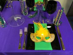 a purple table topped with a black plate covered in masquerade and silverware