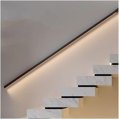 a white staircase with marble steps leading up to the ceiling and lights on either side