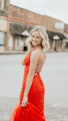 a woman in an orange dress standing on the street