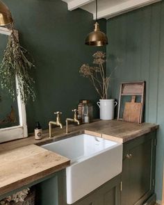 a kitchen with green walls and wooden counter tops, gold faucets and brass fixtures