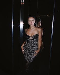 a woman standing in front of a mirror wearing a black and white dress with lace detailing