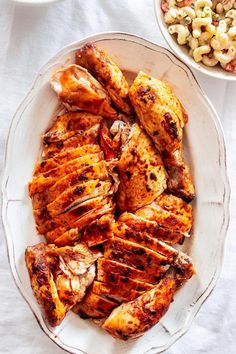 grilled chicken on a plate next to a bowl of macaroni and cheese