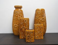 four yellow vases sitting on top of a table