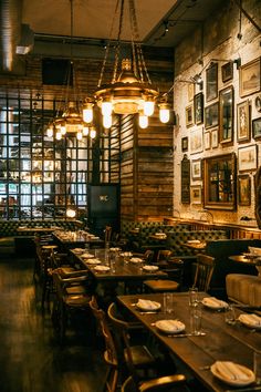 an empty restaurant with wooden tables and chairs, framed pictures on the wall behind them