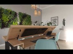 a computer desk with a laptop on top of it in front of a plant wall