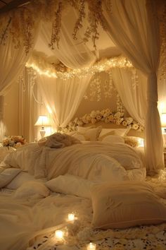 a bed with white sheets and lights on the headboard is decorated with flowers, leaves and petals