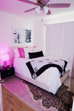 a bedroom with pink and black decor on the walls, white bedding, and rugs