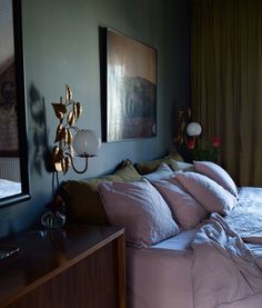 a bed sitting in a bedroom next to a wooden dresser and window covered with curtains