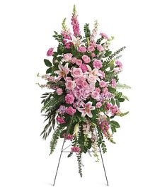 pink flowers and greenery are arranged in a standing spray on a white background,