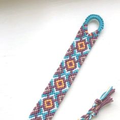 a beaded bracelet with a blue and orange design on it next to a string