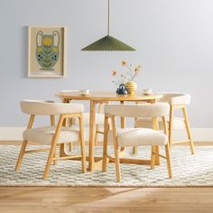 a dining room table with four chairs and a vase on the table in front of it