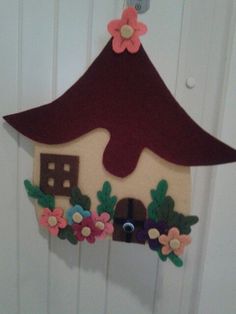 a wooden house with flowers on it hanging from a door handle in front of a white wall