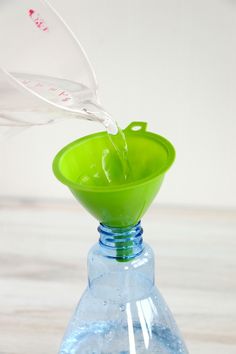 a green glass vase filled with water on top of a table