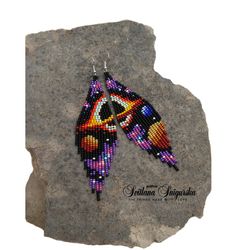 the beaded bird earrings are on top of a rock