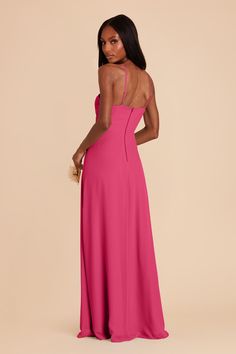 a woman in a pink dress with her back turned to the camera and looking down