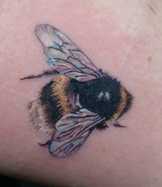 a small tattoo of a bee on the back of a woman's left arm