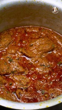 a pot filled with meat and sauce on top of a stove