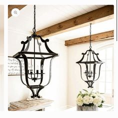 two hanging lights in a room with flowers on the table and an open window behind them