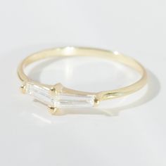 a yellow gold ring with two baguettes on it