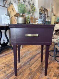 a small table with a drawer on it in a room filled with furniture and other items