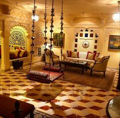 a living room filled with lots of furniture and hanging lights on the ceiling above it