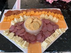 a platter filled with cheese, crackers and sausages on top of it