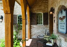 an outdoor patio area with chairs and plants on the side walk, along with a brick walkway