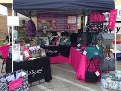 an outdoor market with many bags and purses on display under a tent for sale