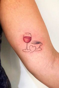 a woman's arm with a wine glass and heart tattoo on it