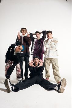 five young men posing for a photo in front of a white background with their hands up