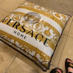 a large pillow sitting on the floor next to someone's black and white shoes