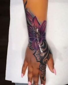 a woman's arm with tattoos on it and a purple flower in the middle