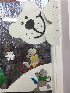 a window decorated with paper cutouts and snowflakes in the shape of animals