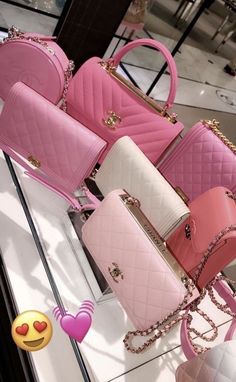 four pink and white purses sitting on top of a glass table next to each other