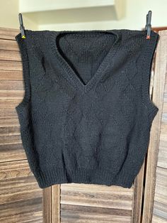 This gorgeous hand knit black wool sweater vest was lovingly created by Georgene Johnson of Hays Kansas. It uses multiple stitches throughout the design. The Unisex sweater vest measures 44 inches wide by 25 inches long.  Care: Dry clean or hand wash cold/gentle cycle. Condition: Very Good Black Fitted Sleeveless Sweater, Fitted Black Sleeveless Sweater, Fitted Sleeveless Black Sweater, Winter Knit Black Vest, Black Knit Winter Vest, Black Knit Vest For Winter, Black Vest Sweater For Fall, Fitted Black Sweater Vest, Black Knitted V-neck Sweater Vest