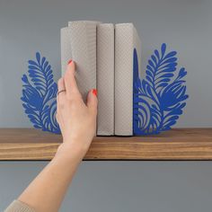 a woman's hand is reaching for two books on a shelf with blue stencils