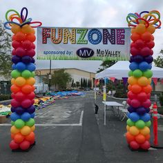 an entrance to a fun zone with balloons and streamers in the shape of bow ties