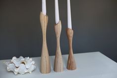 three wooden candlesticks sitting next to each other on a white counter top with shells