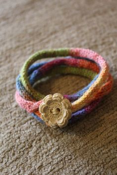 multicolored bracelets with a gold flower on each one and a button in the middle