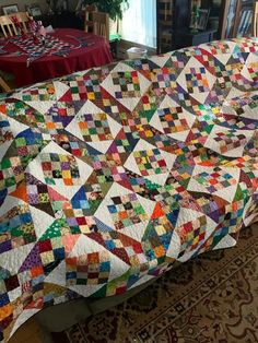 a large quilt is on the floor next to a table