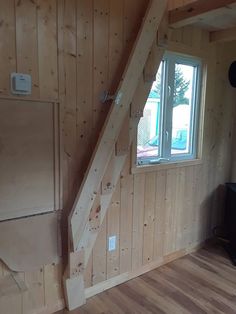 an unfinished room with wood paneling and a window