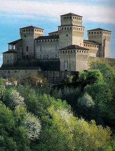 an old castle sitting on top of a lush green hillside