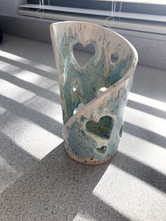 a vase sitting on top of a floor next to a window