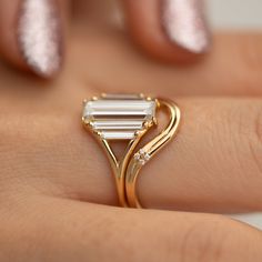 a woman's hand with a gold ring on it and a white diamond in the middle