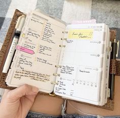 a person holding an open planner book with writing on the pages and notes attached to it