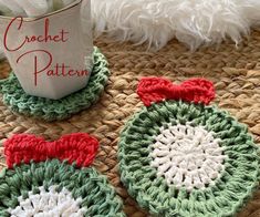 two crocheted coasters with bows on them sitting next to a coffee cup