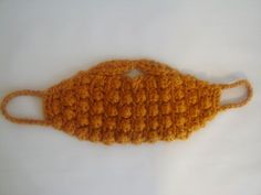 an orange crocheted face mask on a white surface