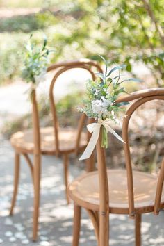 three wooden chairs with flowers tied to them